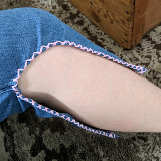 Photo of a leg with jeans with hole cut out with pink hem.