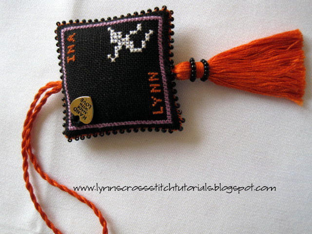 Halloween cross stitched scissor fob tutorial showing black beaded scissor fob with pumpkins embroidered  in cross stitch