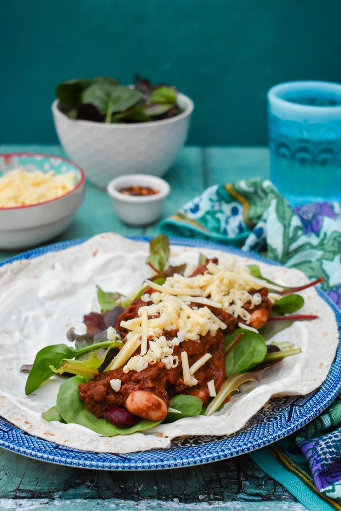Warm tortilla wraps filled with a rich flavourful spiced chilli made with soya veggie mince and beans, layered with salad, vegan cheddar and vegan creme fraiche in place of sour cream. A real family favourite with a printable recipe.
