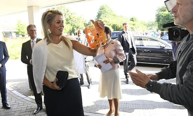 Queen Maxima wore gold tone and shell clip earrings by Prada. Queen Maxima wore a sleeveless high neck silk shirt by Zara, Natan