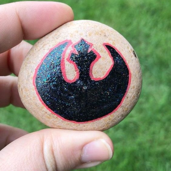 the symbol for the Star Wars resistance painted on a rock