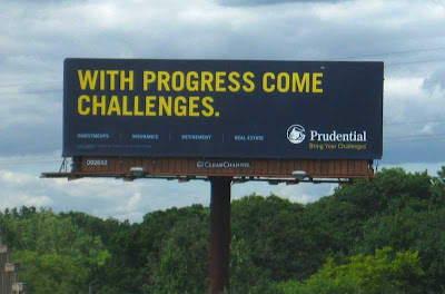 Dark blue billboard with yellow letters reading WITH PROGRESS COME CHALLENGES