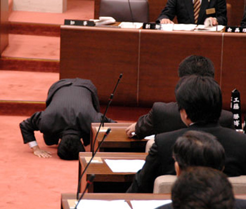 Seorang anggota parlemen Jepang yang sedang berlutut didepan rekan-rekannya