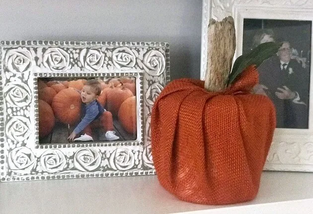 Orange burlap pumpkin next to framed photo of baby with pumpkin.