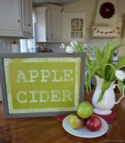 Handmade Green Apple Cider sign in white kitchen with apple and flowers on table.