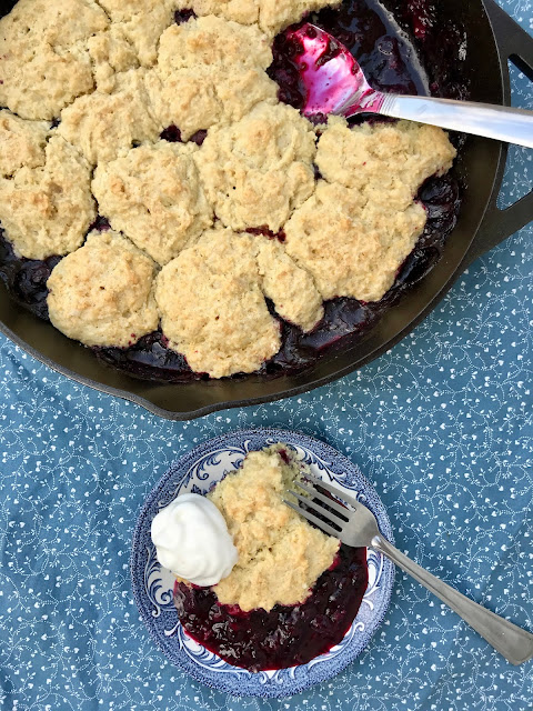 Baked Skillet Sourdough blueberry cobbler with a serving spoon.