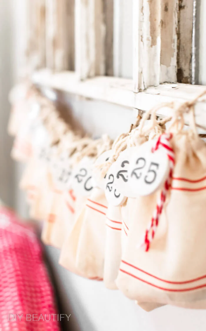 numbered clay circle tags hang from faux grain sack bags for a DIY advent calendar