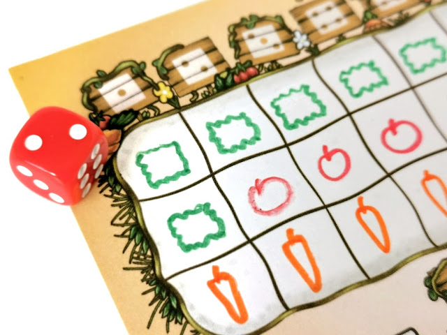 prosta gra kościana dla dzieci z wykreślaniem roll and write prosta gra dla dzieci, na zdjęciu zbliżenie na wypełnioną planszę do gry, obok niej leży czerwona kostka z wynikiem 2