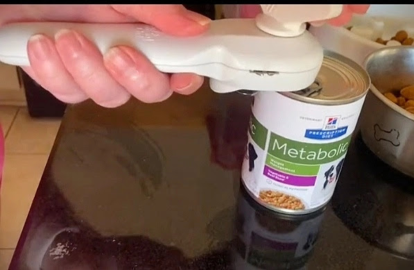 A man holding pampered chef can open and try to open the can