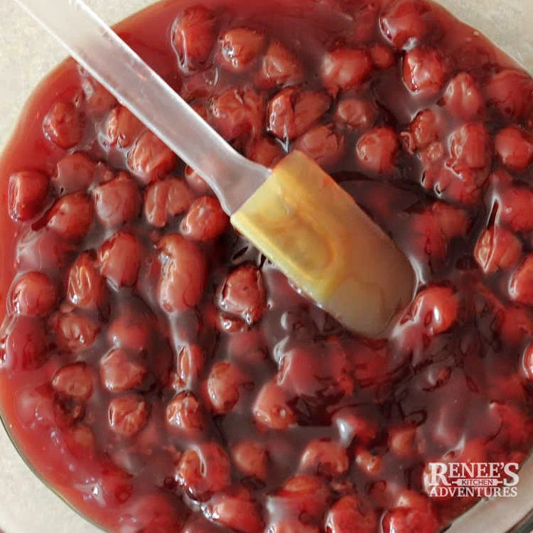 Process image of cherries in pan making Red, white and blueberry dump cake recipe.