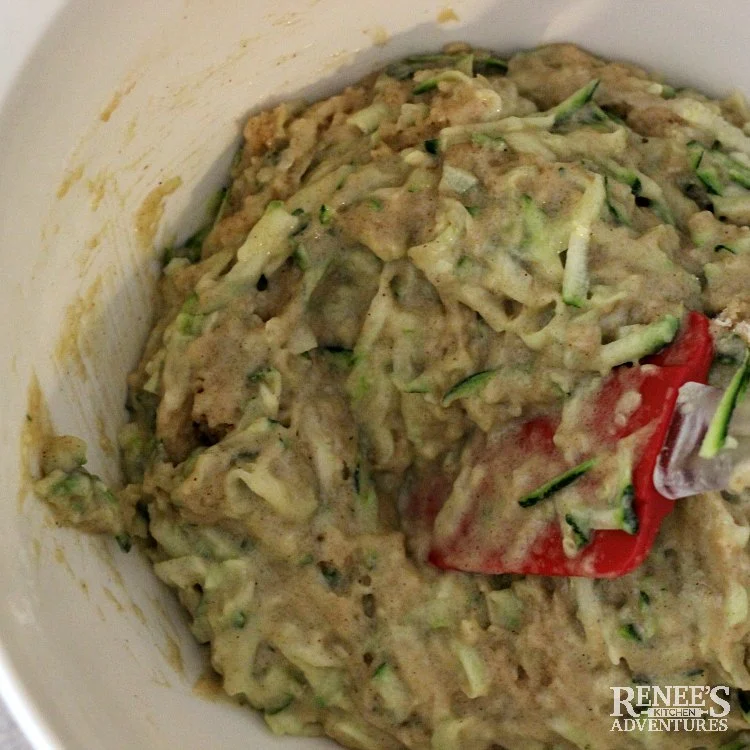 Chocolate Chip Zucchini Muffins by Renee's Kitchen Adventures overhead view of dry ingredients combined with wet ingredients in a white bowl with a red spatula