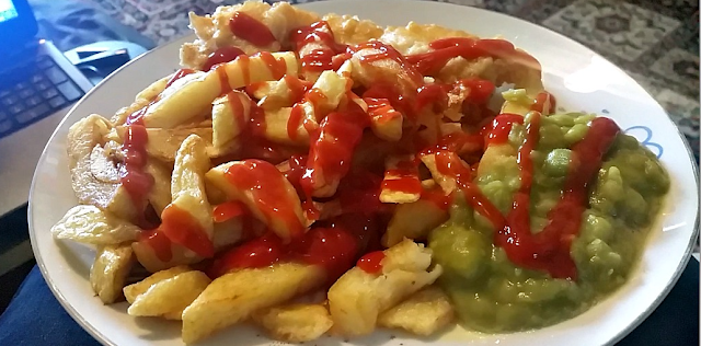 Fish, chips and mushy peas on a plate.