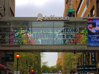 The glass bridge from the outside of the hospital, bearing the words "Alone you are strong.  Together we are stronger," in rainbow colors.