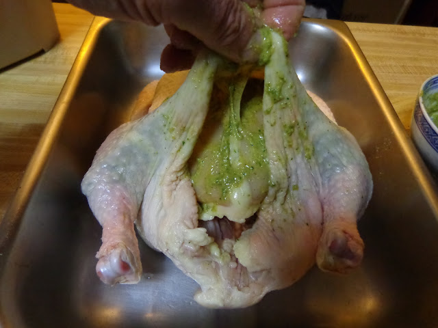 PORTIONS: 4 INGREDIENTS 4 lb. whole chicken 2 cups water or chicken broth 1 cup white wine ½ cube chicken bouillon, without monosodium glutamate 2 tsp. cornstarch CHIMICHURRI PASTE SEASONING INGREDIENTS 1/4 cup chopped onions 3 garlic cloves, chopped 2 tbsp. chopped parsley ½ tsp. dried oregano leaves or 1 tsp. fresh 1½ tsp. salt ½ tsp paprika ¼ tsp ground black pepper ½ tbsp. soften butter 2 tbsp. olive oil METHOD Make the chimichurri paste placing all the ingredients in a blender. Lately it is recommended not to wash the chicken, for the risk of contamination when the water splashes on other surfaces. I’m sorry, but I rinse the chicken inside and out, with cold water. Pat dry the chicken with paper towels and place it in a dish temporarily. Then clean with soap and water the entire area of the sink or surfaces that may have been contaminated. With your fingers, separate the skin from the breast and thighs without tearing it apart. Using a teaspoon spread the ½ the chimichurri underneath the skin, around the breast and thighs. Spread the rest of the chimichurri over the chicken skin. Bend the wings under the chicken and tight the chicken legs with a kitchen twine. Pour the water and wine in a pot. Bring it to a boil and dissolve the chicken bouillon. Place the liquid in a roasting pan and put a griddle on top. Place the chicken on top of the griddle. Preheat the oven at 325°F / 163°C Roast the chicken for about 90 minutes. Baste the chicken every 20 minutes. The chicken should have a minimal internal temperature of 165°F / 74°C or if you pierce it with a skewer the juices should run clear, cook until golden brown. Pour the juices in a fat separator discard as much fat as possible. Pour the liquid in a pot and bring it to a boil. Mix the cornstarch with 1 tbsp. of water and mix it into the liquid. Let the sauce cook for 3 minutes.  Untie the legs, carve the chicken and serve with the sauce.