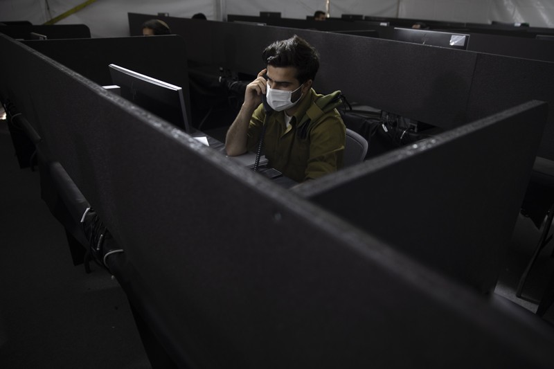 An Israeli soldier in a call centre in Ramla talks on the phone to a person infected with coronavirus to try to identify their contacts