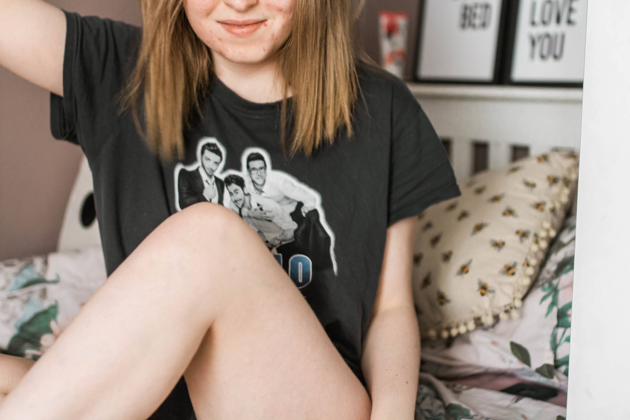girl in il volo band tee sitting on bed
