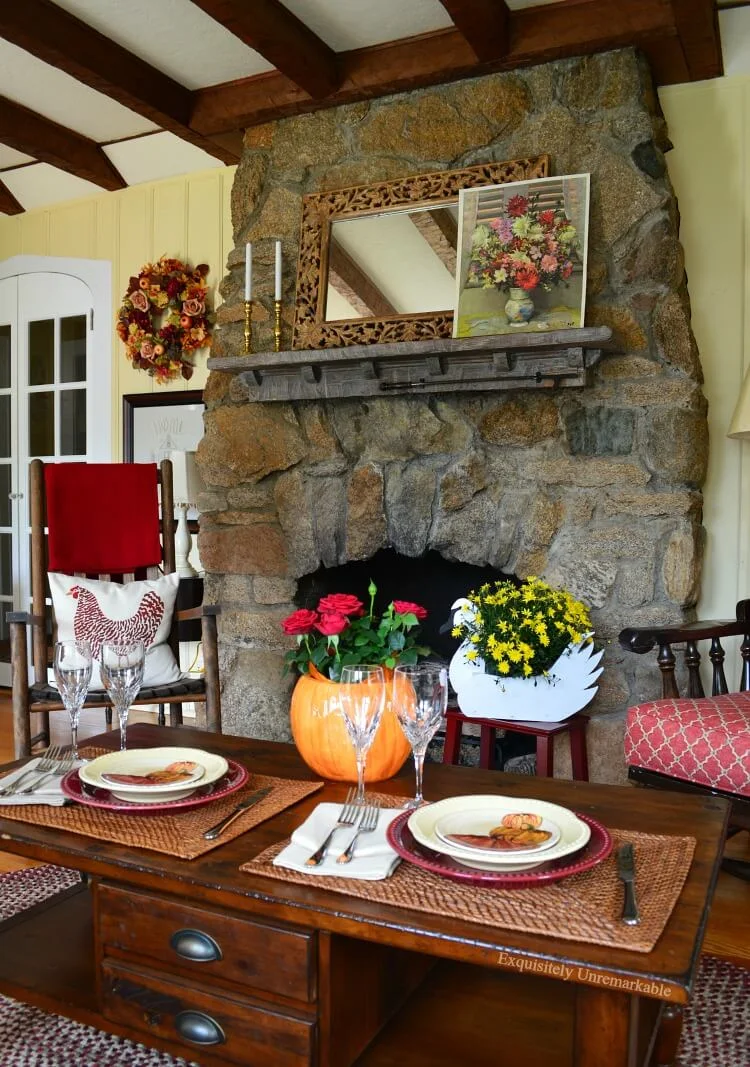 Fall living room with stone fireplace and beams on ceiling