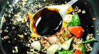 Pouring soya sauce with red chilli sauce, vinegar and vegetables for chilli chicken
