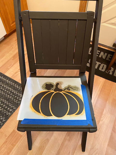 Photo of a wooden chair being stenciled with a pumpkin stencil