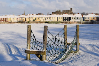 A rope bridge in the play area covered in snow