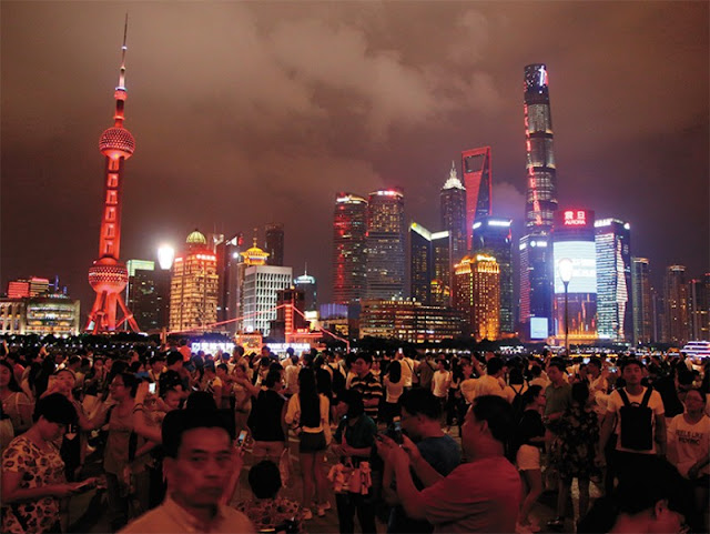 Район Пудун в Шанхае, самом большом по числу населения городе мира, который одновременно является и крупнейшим морским портом. Здесь на набережной, чем-то напоминающей Гонконг, вечером празднично и многолюдно.