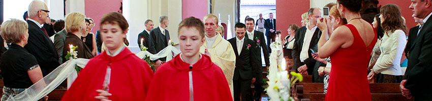 ministranci ksiądz i para mloda idą przez kościół