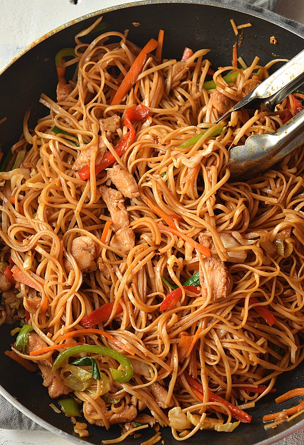 Better Than Takeout Chicken Lo Mein! You love Asian food or Chinese food takeout then this recipe is calling your name with easy steps and ready under 30 mins! Delicious soft juicy Chicken cooked along with vegetables like Red Bell Peppers,Spring Onions,Garlic,Ginger,Onion,Carrot and Cabbage tossed together with Egg Noodles in sauces made from Soy Sauce,Sriracha and Oyster sauce #savorybitesrecipes #easy #food #chinese #takeoutfood #lomein #dinnerideas a pan with chicken lo mein along with veggies,sauces tossed together