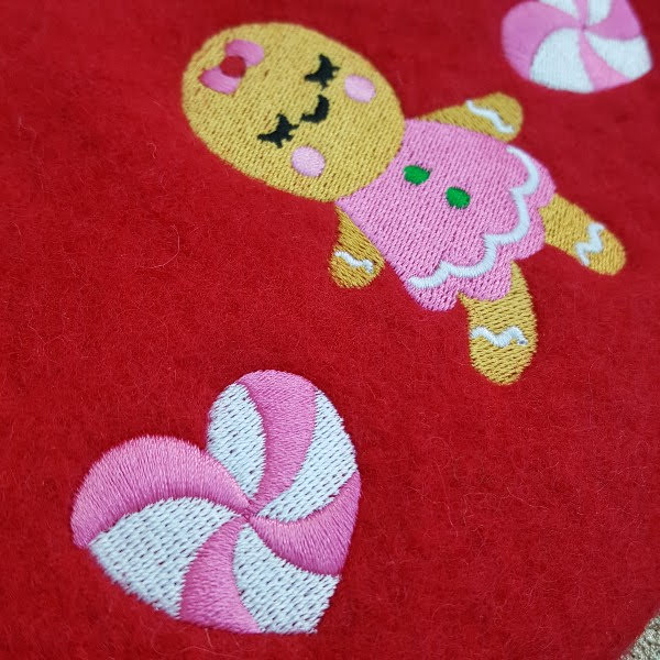 close up of candy swirl hearts and gingerbread girl embroidered on red wool beret