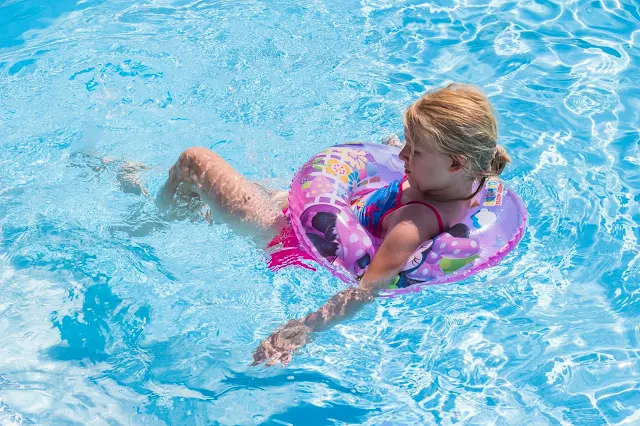 A 6 year old in a rubber ring floating around in a swimming pool