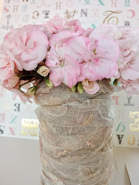 Flores de geranio en bote de cristal enrollado con cinta de blonda de color rosa