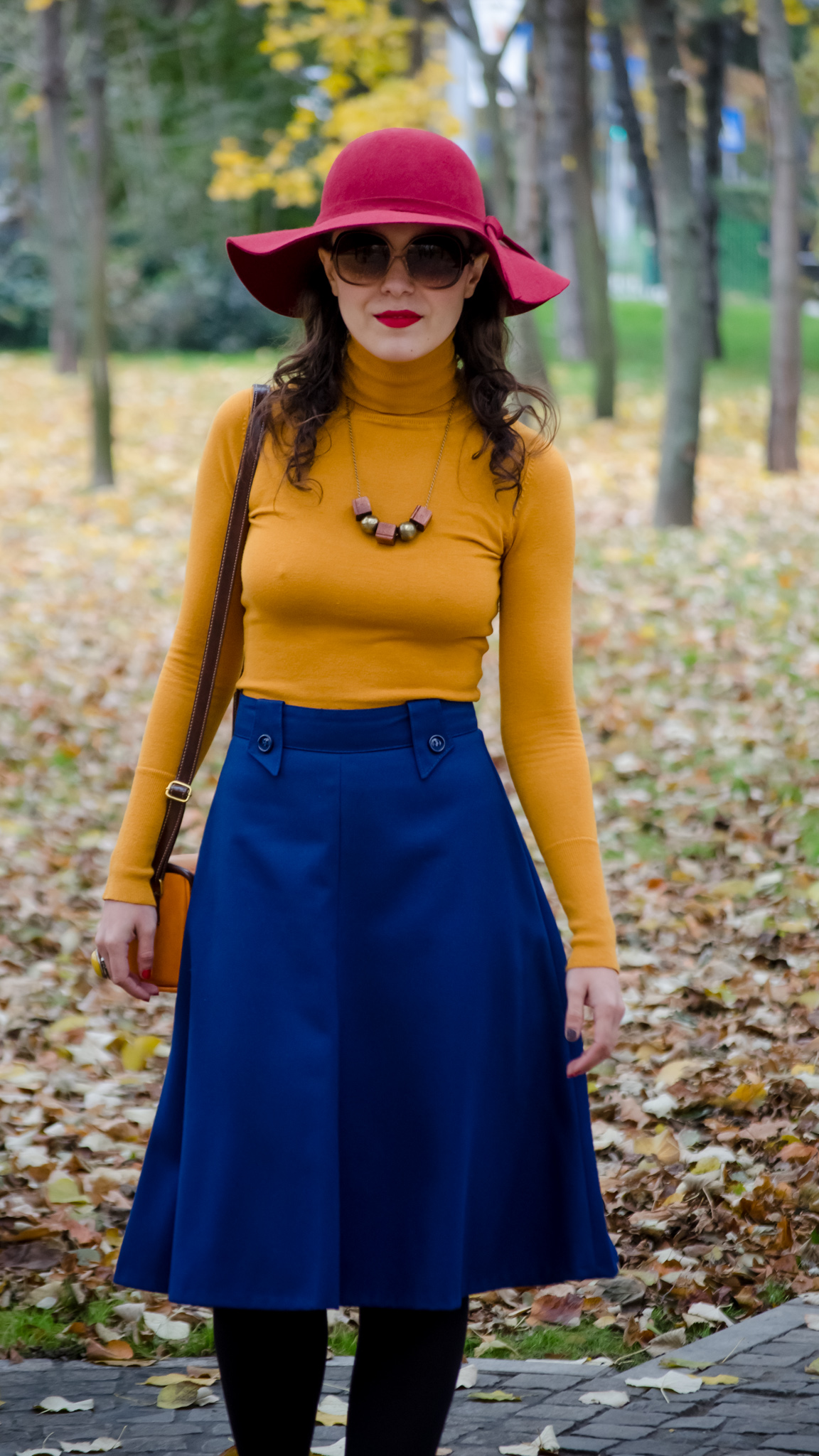 blue skirt mustard turtleneck sweater burgundy floppy hat brown jacket box satchel mustard heels autumn fall scenery leaves