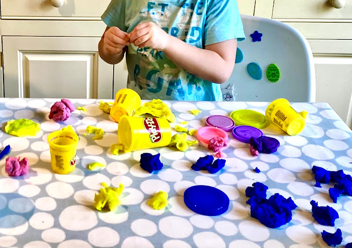 play-doh mess Blue, yellow and pink play-doh all over a table in separate clumps