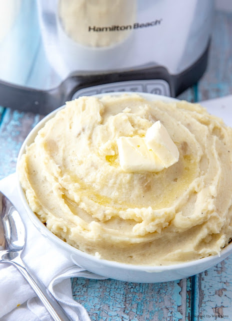 Creamy mashed potatoes in white bowl with a pat of butter