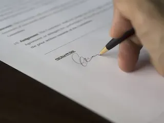 imagem de uma mão segurando uma caneta que assina um documento ilustrando a página do saberimobiliriario