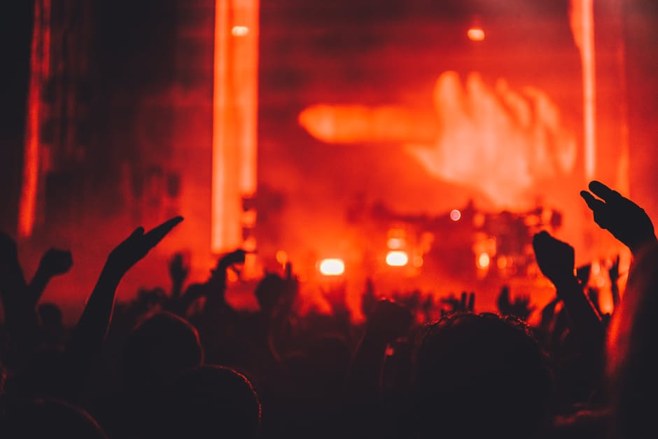 People Standing Raising Their Hands in Front of Red Stage