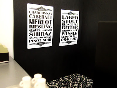 Modern one-twelfth scale miniature bar scene with black and white posters listing drink types on the side wall.