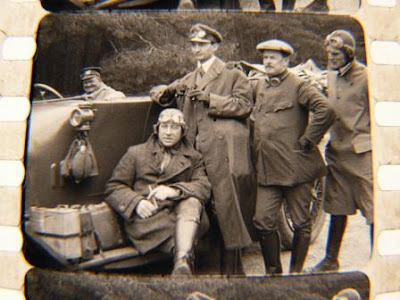 Airmen from The Great War posing by car with driver at wheel.