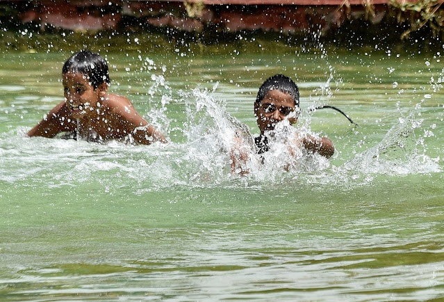 Children take bath in a pond to beat the heat near India Gate during a hot summer day, in New Delh