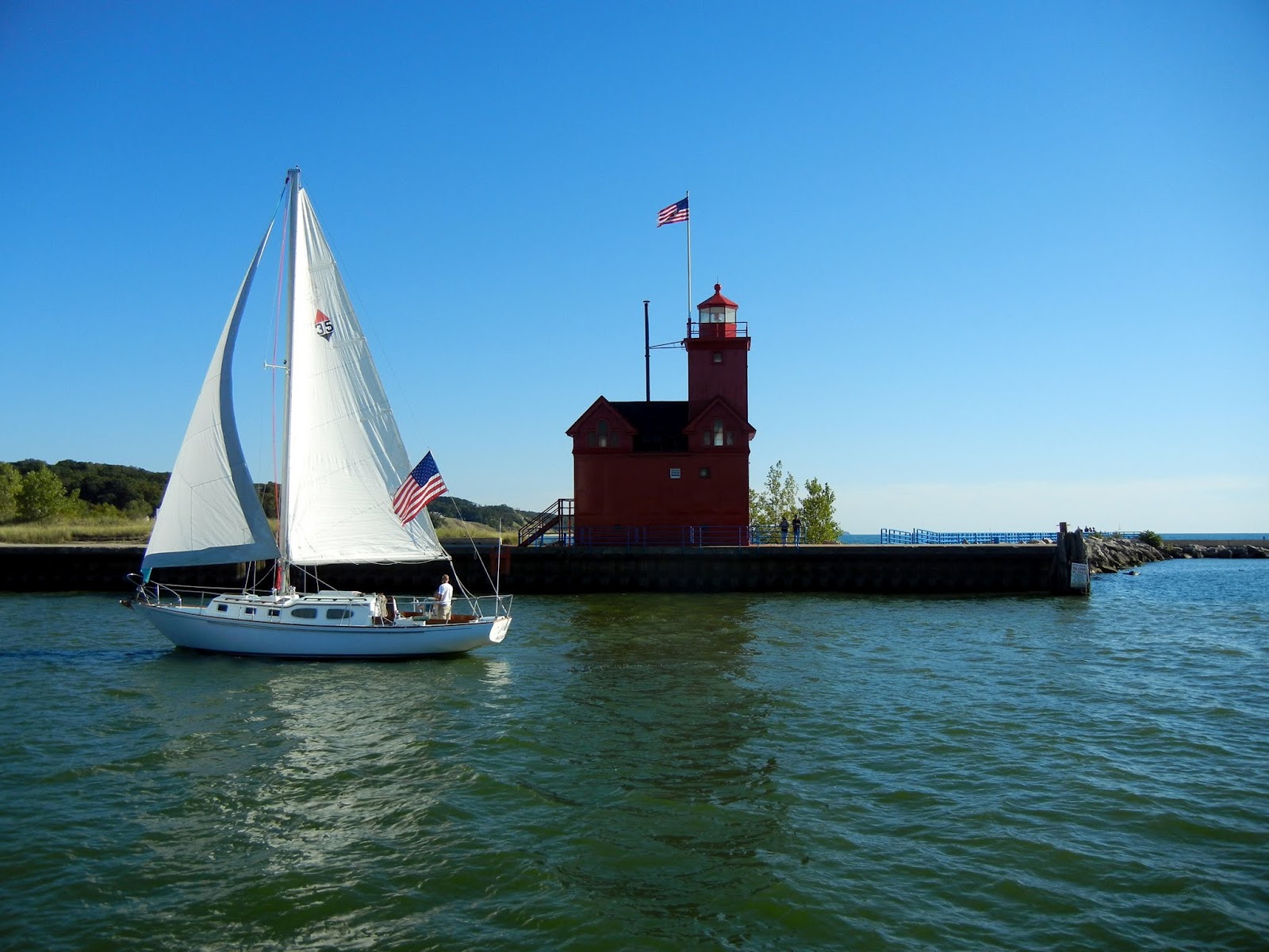 Sailboat coming from Lake Michigan in front of Big Red Lighthouse