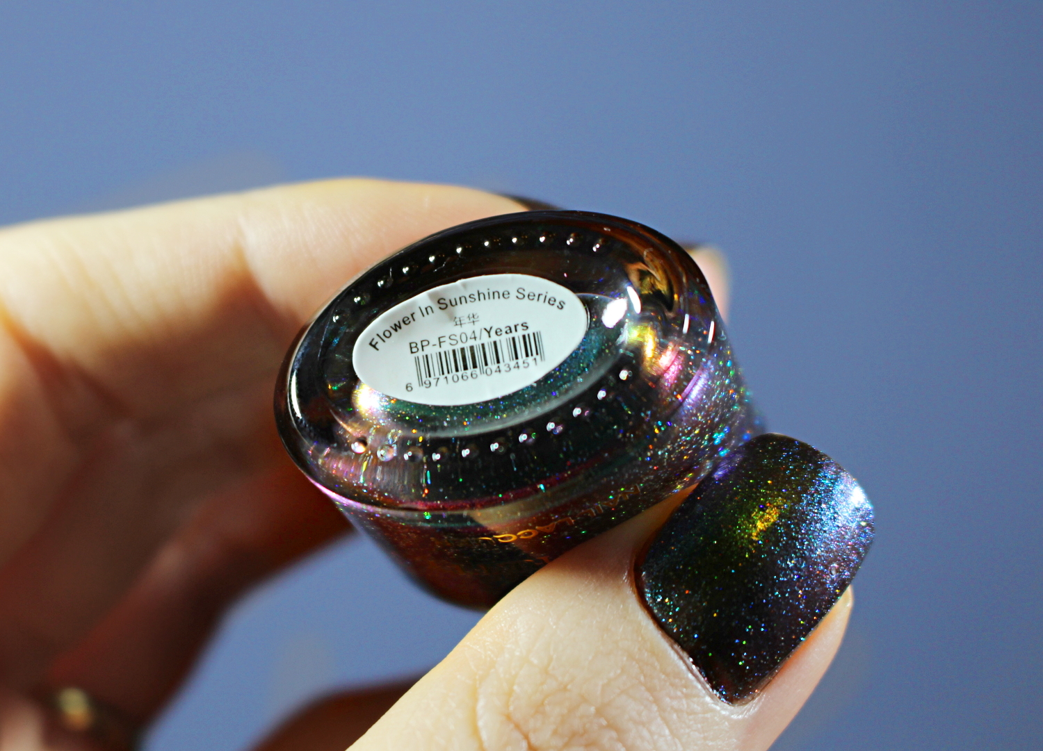 a close-up of a green holographic nail look on short natural nails