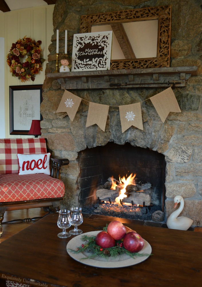 Stone fireplace lit and decorated for Christmas with a snowflake banner