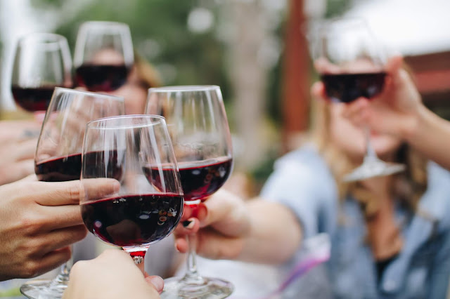 happy people are toasting with red wine glasses