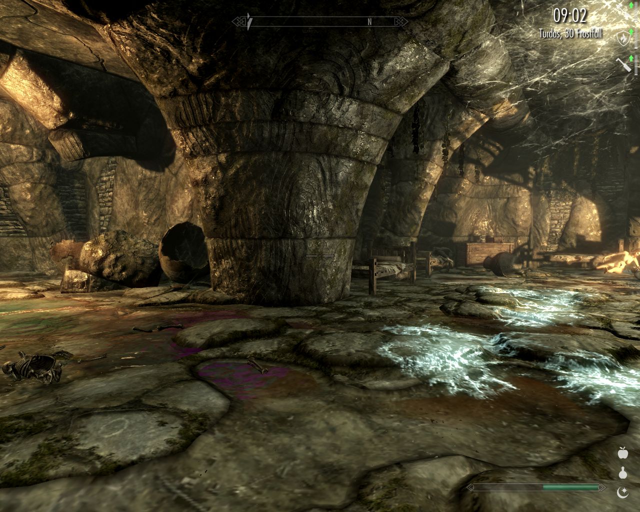 large room with thick stone columns, dirty floor, one dead body near beds in the farther end