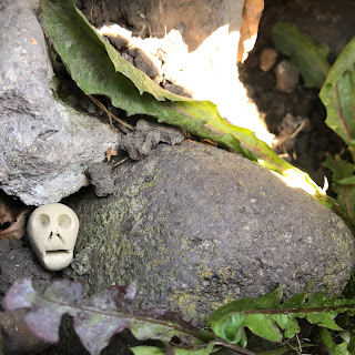 A photo of a Skulferatu, a small ceramic skull amongst the rocks of Muschet’s Cairn, Holyrood Park, Edinburgh.  Photo by Kevin Nosferatu for the Skulferatu Project