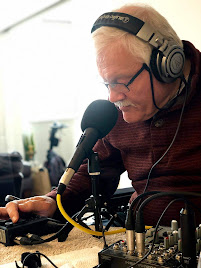 Picture of Phil wearing headphones and talking into a microphone.