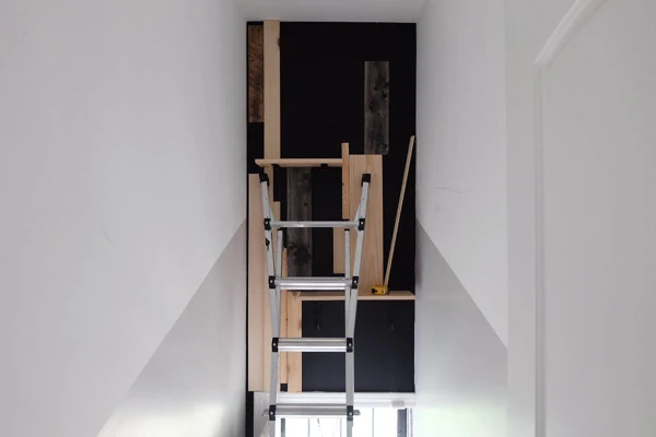 tacking wood pieces to black painted wall