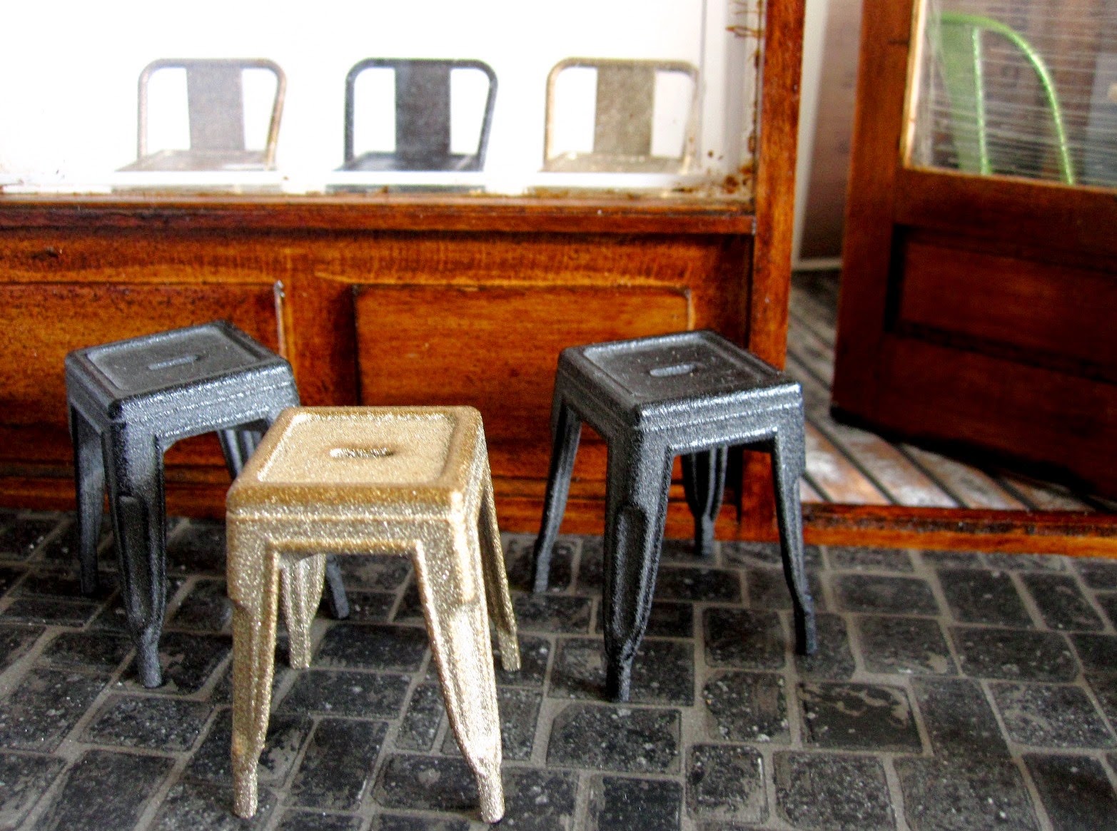 Modern dolls' house miniature cafe front with metal cafe chairs and stools.