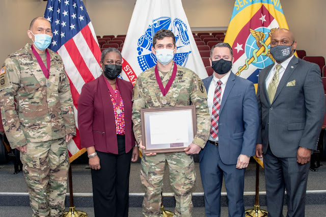 A group of people stand and present an award