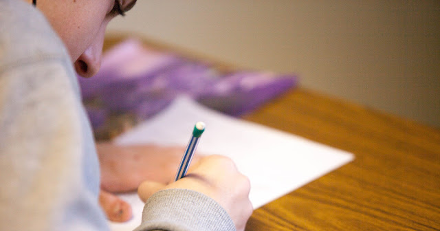 Student hovers over a test in a classroom