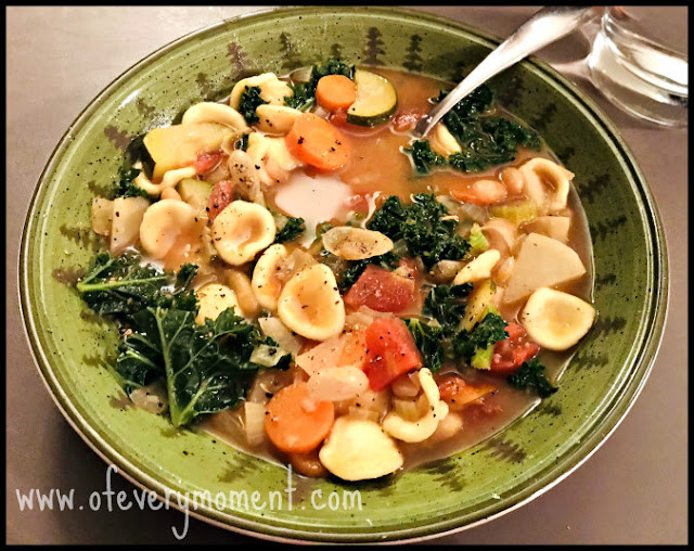 A bowl of vegetable soup with pasta, beans and greens